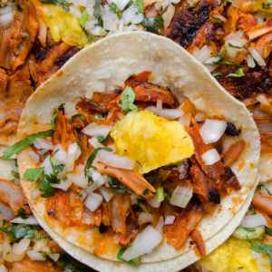 A zoomed in taco al pastor with severla others surrounding it.